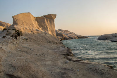 Rock formations on shore against clear sky