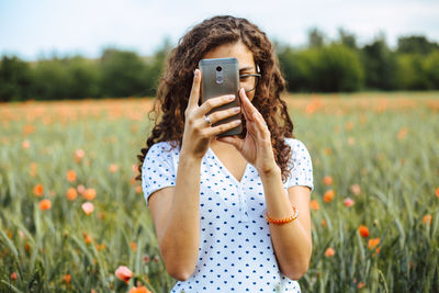 Midsection of woman photographing with smart phone in field