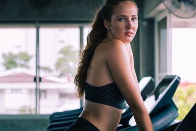 Side view of young woman exercising on treadmill in gym
