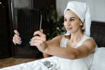 Beauty blogger, vlogger, influencer. young woman in pajamas, towel on her head and with cosmetic