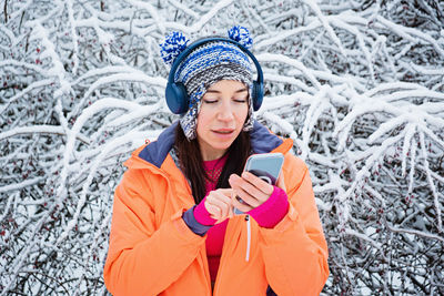 Sporty fitness woman listening music with headphones outdoors in winter park. active woman jogging