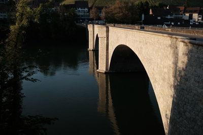 Arch bridge over river against trees