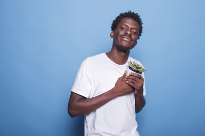 Portrait of young man standing against blue background