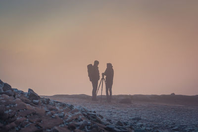 People on sand dune in desert against sky