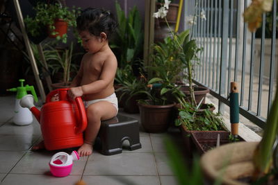 Midsection of shirtless man sitting in potted plants