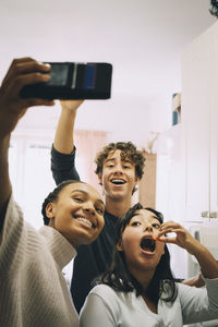 Portrait of smiling man photographing with smart phone