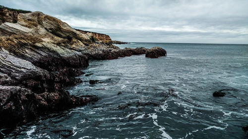 Rock formation in sea against sky