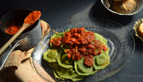 High angle view of spinach ravioli with red marinara sauce in plate on table