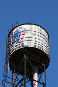 Low angle view of water tower against clear blue sky