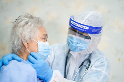 Doctor wearing protective suit examining patient in hospital