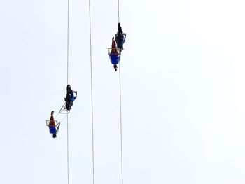 Low angle view of men performing stunt on ropes