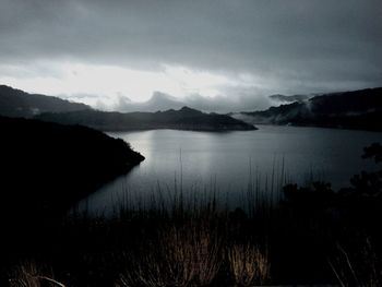 Scenic view of lake and mountains against cloudy sky