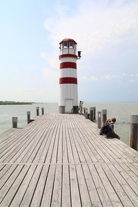 Lighthouse by sea against sky