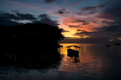 Silhouette boat in sea against sky during sunset