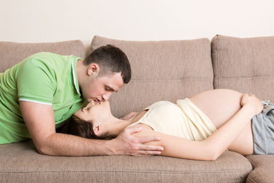 Side view of young couple relaxing on sofa at home