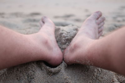 Low section of woman relaxing on sandy beach