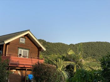 House and trees on landscape against clear sky