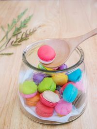 High angle view of multi colored macaroon with wooden spoon in jar