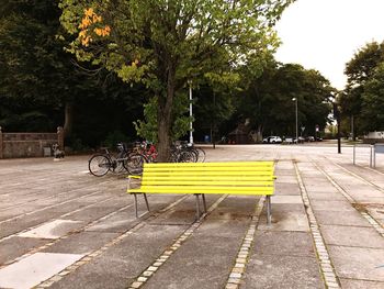 Bicycle parked by trees in city against sky