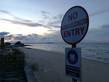 Information sign by sea against sky