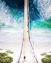 Aerial view of footbridge hanging over sea