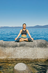 Young woman practicing yoga on lake tahoe in northern california.