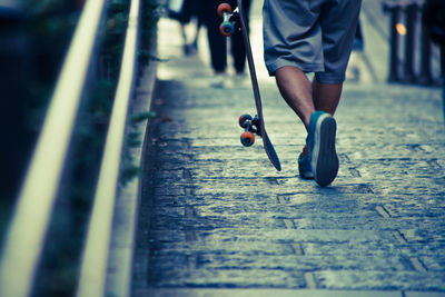 Rear view low section of skateboarder walking on road