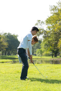 Full length of couple playing golf on field