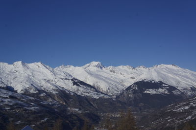 Scenic view of snowcapped mountains against clear blue sky