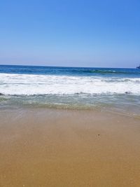 Scenic view of beach against clear blue sky