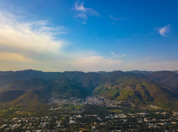 Aerial view of townscape by mountains against sky