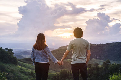 Rear view of friends standing on mountain against sky