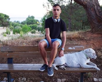 Full length of man with dog sitting on bench at park