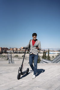 Portrait of young man in city against clear sky