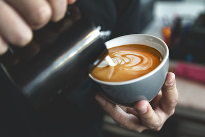 Barista preparing cafe latte, pouring milk into a coffee. closeup on latte art.