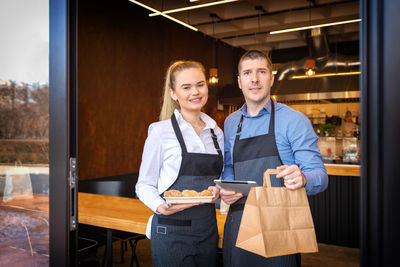 Portrait of smiling owners standing in restaurant