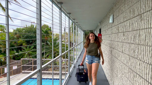 Full length of young woman standing against building