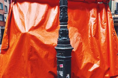 Close-up of orange bell hanging on metal structure