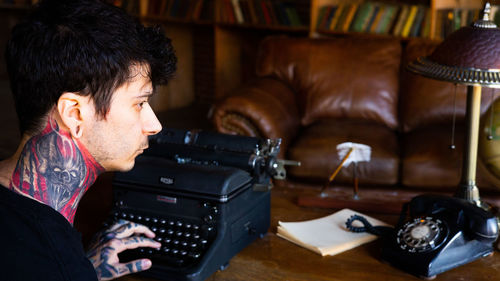 Side view of young man using typewriter