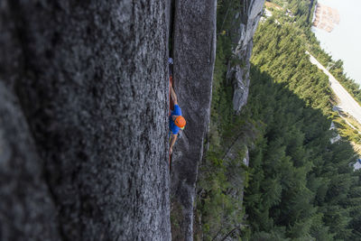 Climber placing protection in wide crack high up the chief in squamish