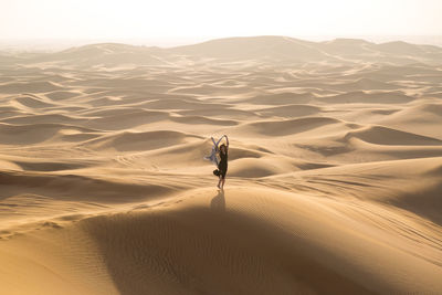 Full length of woman standing on sand dune in desert