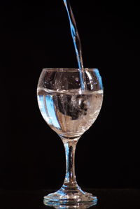 Close-up of wineglass on glass against black background