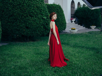 Woman with red umbrella standing on grass