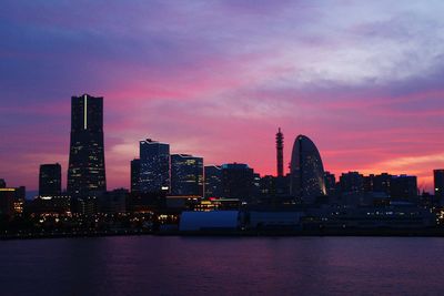 Modern buildings in city against dramatic sky during sunset