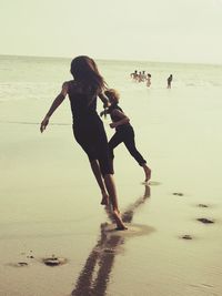 People walking on beach against clear sky