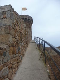 Footpath by wall against sky