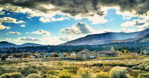 Houses on field against cloudy sky