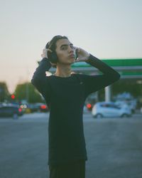 Side view of young man standing against sky