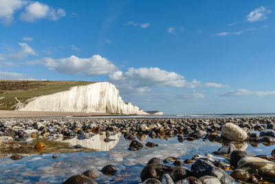 Group of people on rock by sea against sky