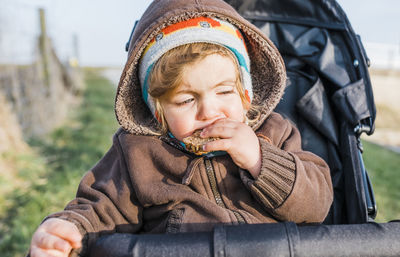 Close-up of girl eating food while sitting in baby stroller